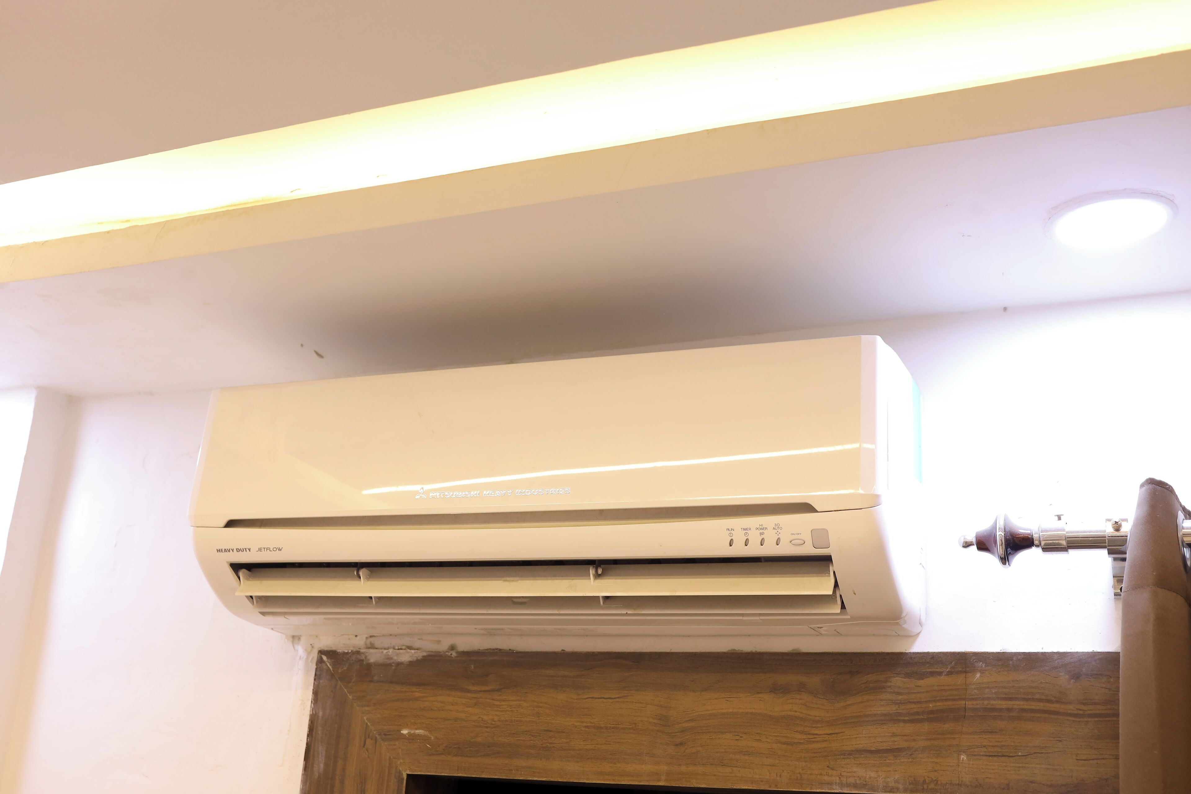 An air conditioning unit mounted on a wall with a wooden panel below.
