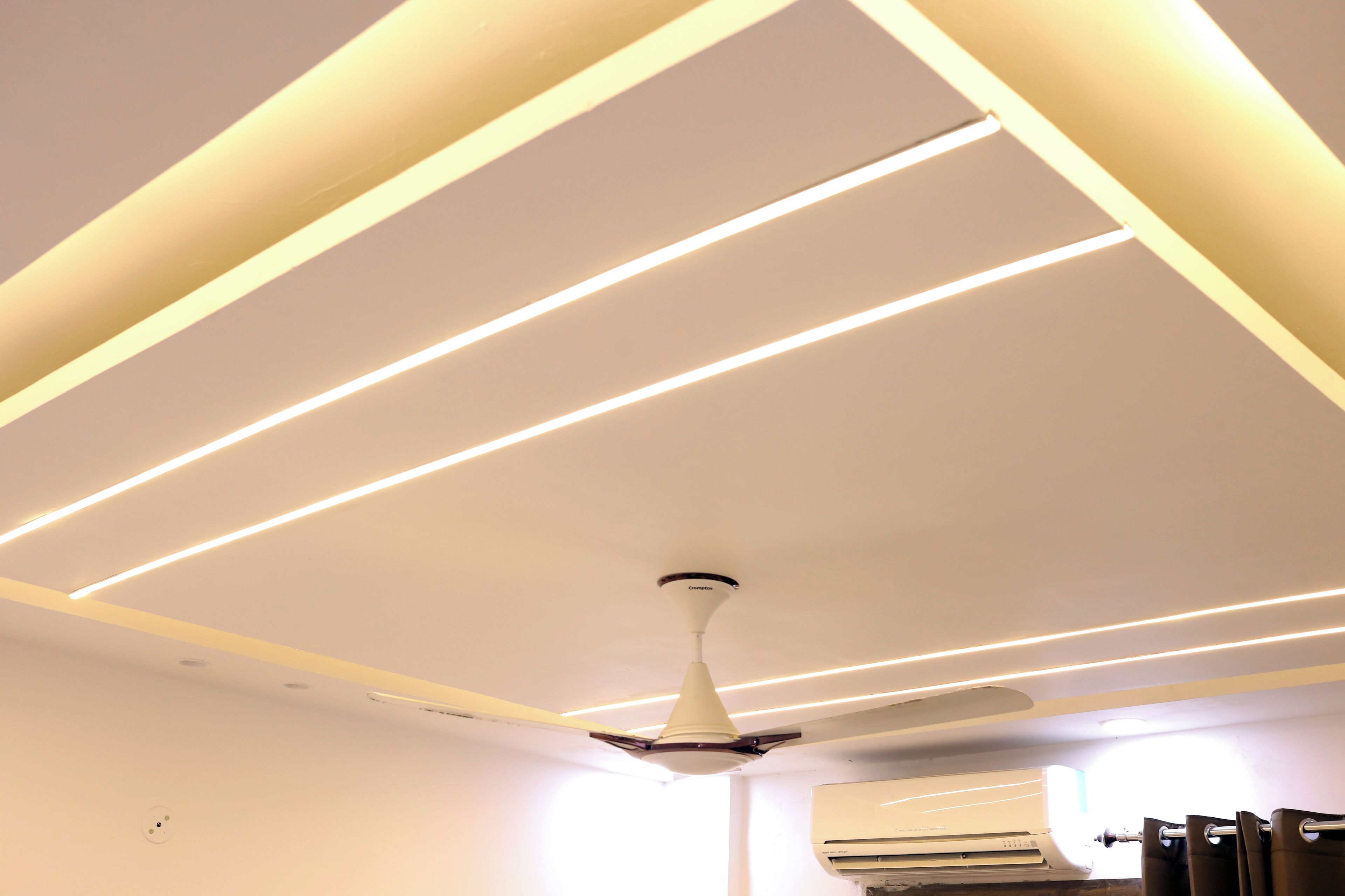 A ceiling with linear lighting fixtures and a ceiling fan.