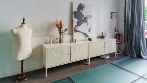 A room with a mannequin, a cabinet, a vase with flowers, a painting, and a fire extinguisher.