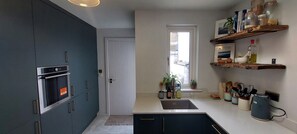 Et moderne køkken med mørke skabe, en indbygget ovn og et vindue med udsigt.