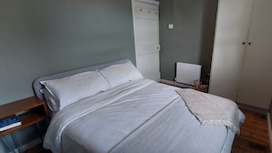 Ein Schlafzimmer mit einem Bett, einem Nachttisch, einem Heizkörper und einem Kleiderschrank.