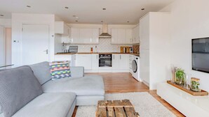 Une cuisine moderne avec des meubles blancs, un four encastré et un lave-linge.
