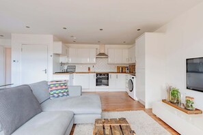A modern kitchen with white cabinets, a built-in oven, and a washing machine. - Contemporary 2BD Flat with Balcony, Shoreditch (Greater London)