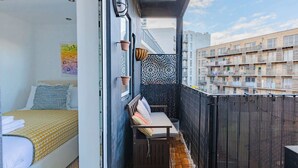 Un balcon aménagé avec un lit, un banc et un mur décoratif.