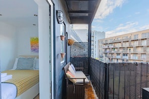Un balcon aménagé avec un lit, un banc et un mur décoratif.