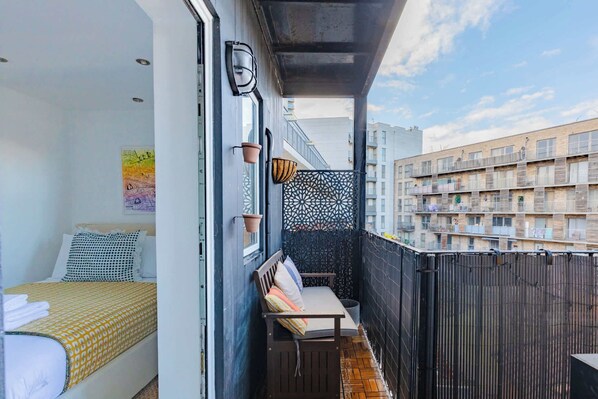 Un balcon aménagé avec un lit, un banc et un mur décoratif.