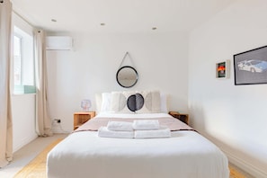 A neatly arranged bedroom with a bed, bedside tables, a wall-mounted mirror, and a framed picture. - Contemporary 2BD Flat with Balcony, Shoreditch (Greater London)