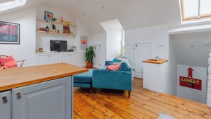 A modern living space with a kitchen area, a blue sofa, and a dining table.