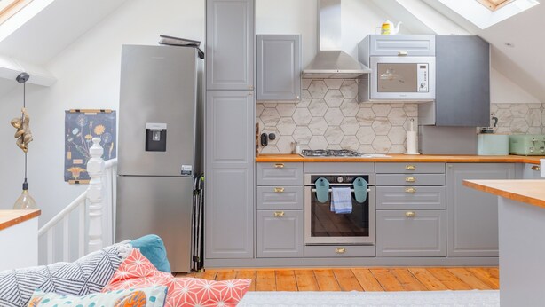A compact kitchen with grey cabinets, a built-in microwave, and a gas stove.