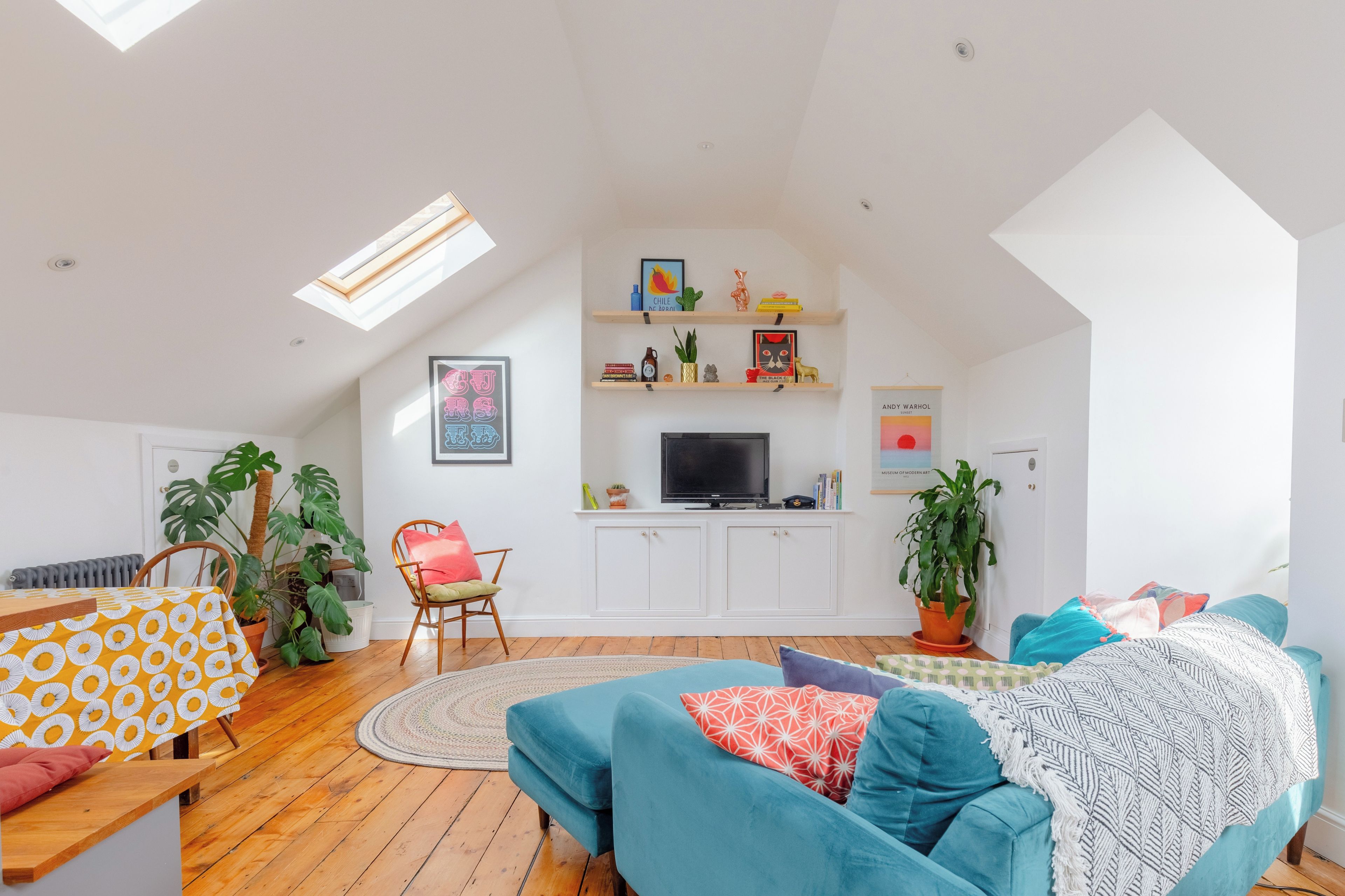 A spacious living room with a high ceiling, a television, and various decorative items.