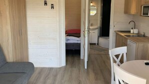 Een compacte kamer met een bed, een kleine kitchenette en een zithoek.