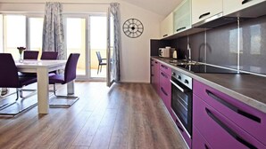 A modern kitchen with stainless steel appliances, a dining area with a table and chairs, and a large window with curtains. - Apartment in Starigrad Near Beach & Paklenica (Starigrad)