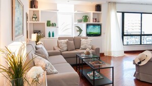 Un soggiorno moderno con divano, tavolino e mensole decorate con oggetti vari.