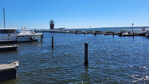 Un puerto deportivo con barcos amarrados, un faro y un cielo azul despejado.