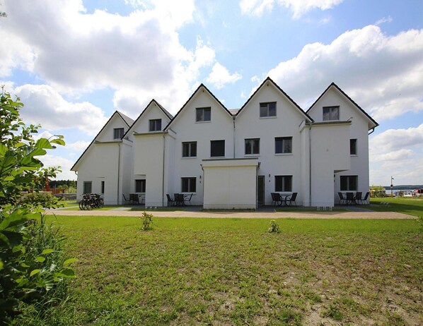 Um edifício branco de vários andares com fachada simétrica, várias janelas e telhado plano.