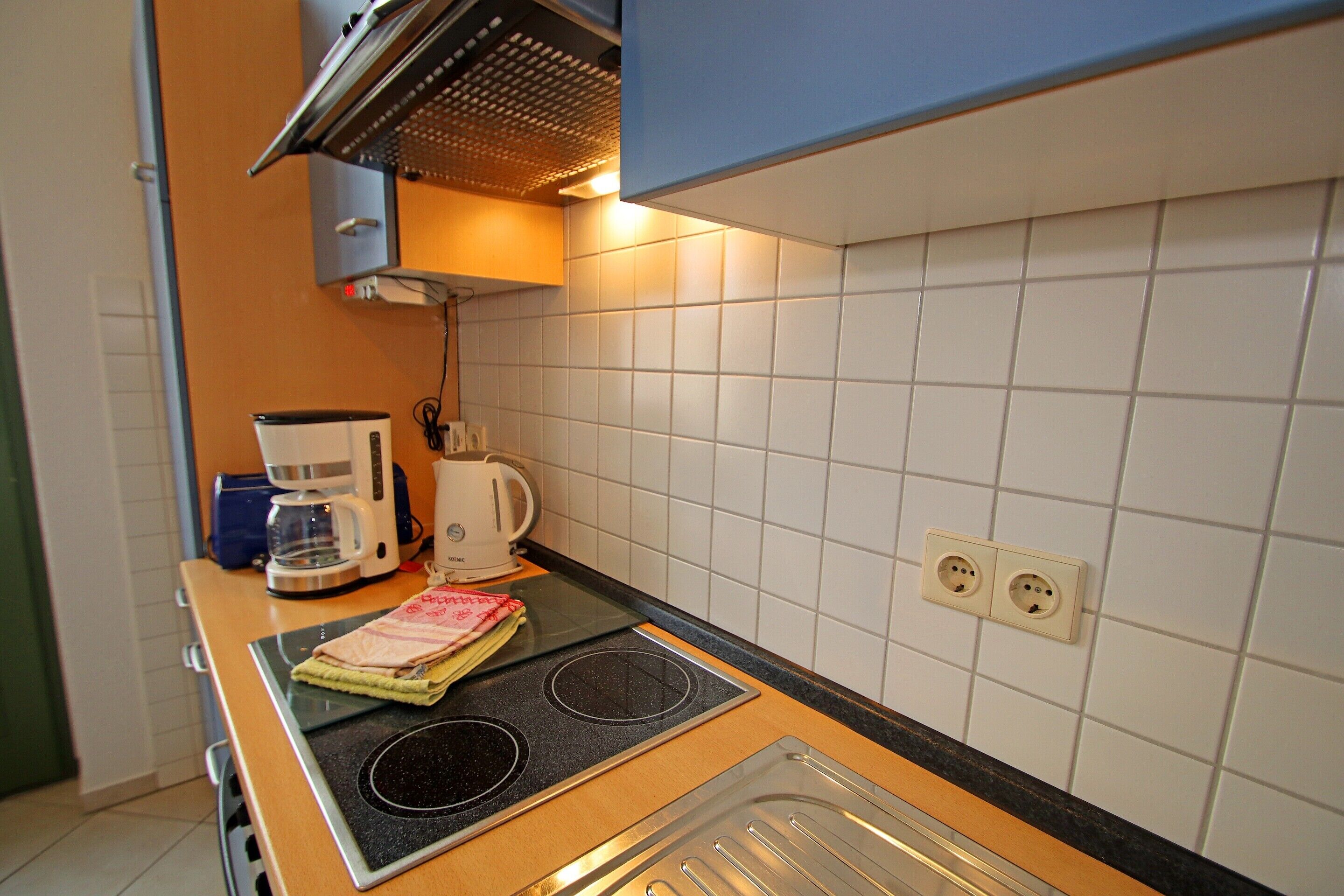 Ett kök med en spis, en kaffebryggare och en vattenkokare.
