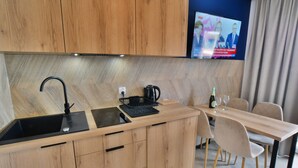 A modern kitchen with wooden cabinets, a black sink, and a built-in TV above the counter. - Comfortable Apartment With a sea View (Ustronie Morskie)