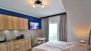 A modern hotel room with a kitchenette, a bed, a dining area, and a TV. - Comfortable Apartment With a sea View (Ustronie Morskie)