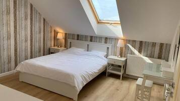 Cozy retreat with a large bed, bedside tables, and a desk for work or study, set against rustic paneling.
