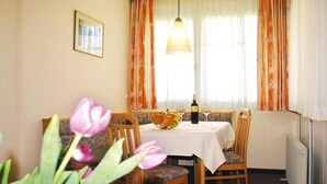 En spiseplads med et bord dækket til to, en vase med tulipaner og et vindue med gardiner.