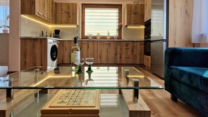 Een moderne keuken met houten kastjes, een glazen eettafel en een blauwe bank.