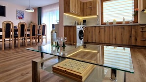 Een moderne keuken met houten kasten, een glazen eettafel en een ingebouwde wasmachine.
