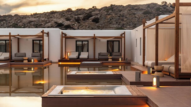 A modern outdoor pool area with multiple seating arrangements and a view of a rocky hillside. - Laguna Coast Resort, Small Luxury Hotels of the World (Naxos)