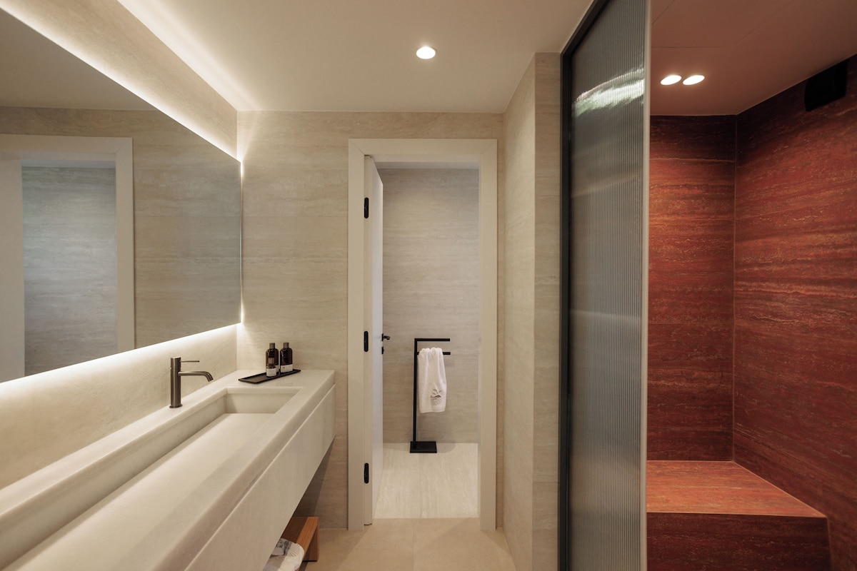 A modern bathroom with a large mirror, a white sink, and a shower area.
