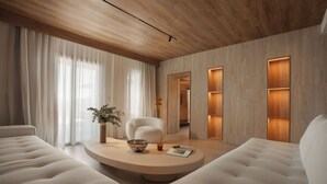 A modern living room with a round coffee table, two white sofas, a white armchair, and a wooden ceiling. - Laguna Coast Resort, Small Luxury Hotels of the World (Naxos)