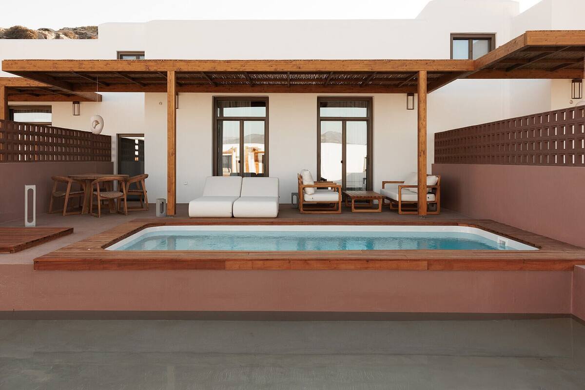A rooftop pool area with a wooden deck, white lounge chairs, and a wooden pergola.