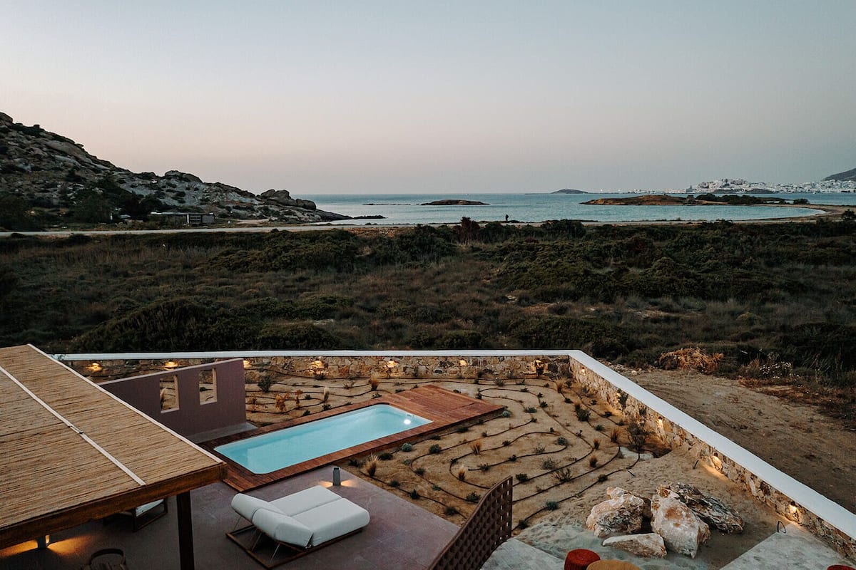 A rooftop pool area with a lounge chair, a small pool, and a view of the coastline.