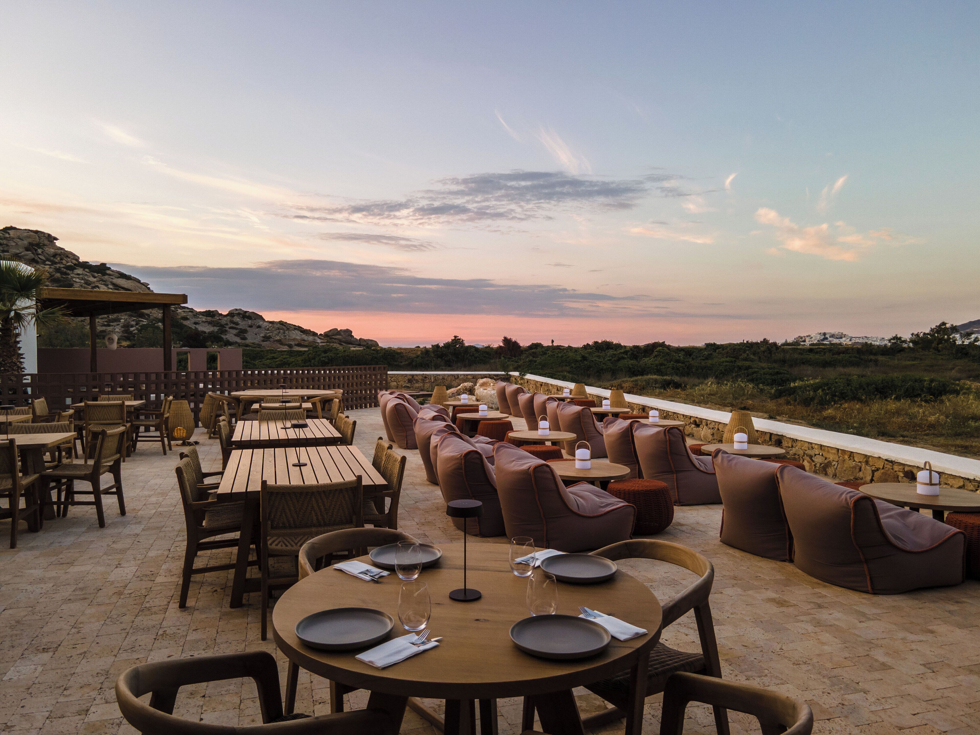 An outdoor dining area with tables and chairs, overlooking a scenic landscape.