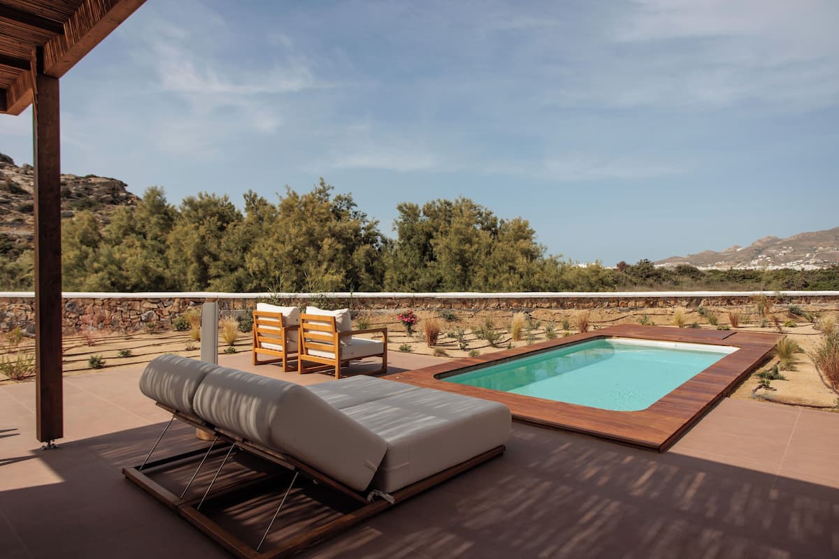 A poolside area with a wooden deck, a lounge chair, and a small table.