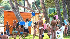 A group of people in a grassy outdoor area with trees and a wooden structure. - Residence Cormoran, Loc. Campus Villasimius (Villasimius)