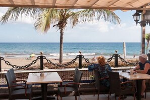 Ein Café direkt am Strand mit Tischen und Stühlen, mit Blick auf den Ozean.