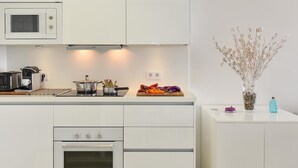 A modern kitchen with white cabinetry, a microwave, a coffee maker, and a stove. - Apartment, San Agustin (San Bartolomé de Tirajana)
