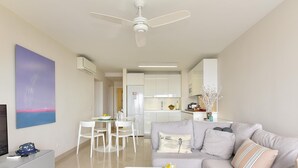A modern living room with a glass coffee table, a sofa, and a dining area with white chairs. - Apartment, San Agustin (San Bartolomé de Tirajana)
