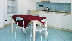 A small kitchen with a dining table, chairs, and a stove. - Apartment in Mongelia (Moneglia)