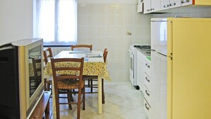 A compact kitchen with a dining table, chairs, a refrigerator, and a television. - Apartment in Mongelia (Moneglia)