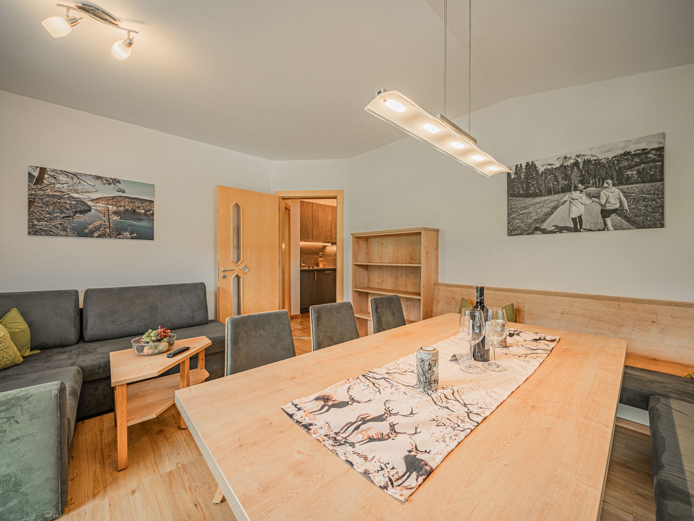 Un salon moderne avec un coin repas, des meubles en bois et des œuvres d’art accrochées aux murs.