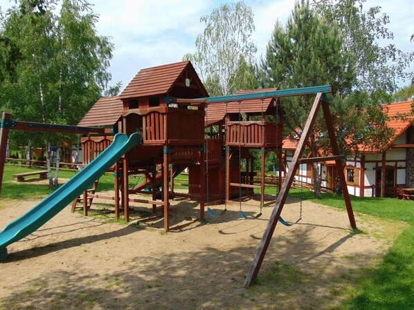 A wooden playground structure with a slide and swings.