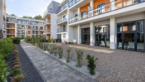 Ein modernes Mehrfamilienhaus mit mehreren Balkonen, einem gepflasterten Weg und einem kleinen Garten.