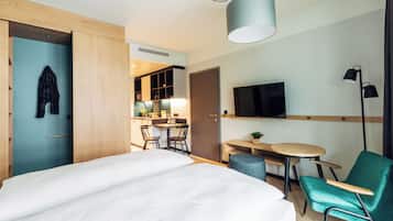 Una habitación de hotel moderna con una cama, un escritorio, una silla, un televisor y un rincón de comedor.