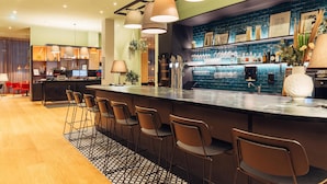 Un área de bar moderna con una barra larga, varios taburetes y un revoque de azulejos.