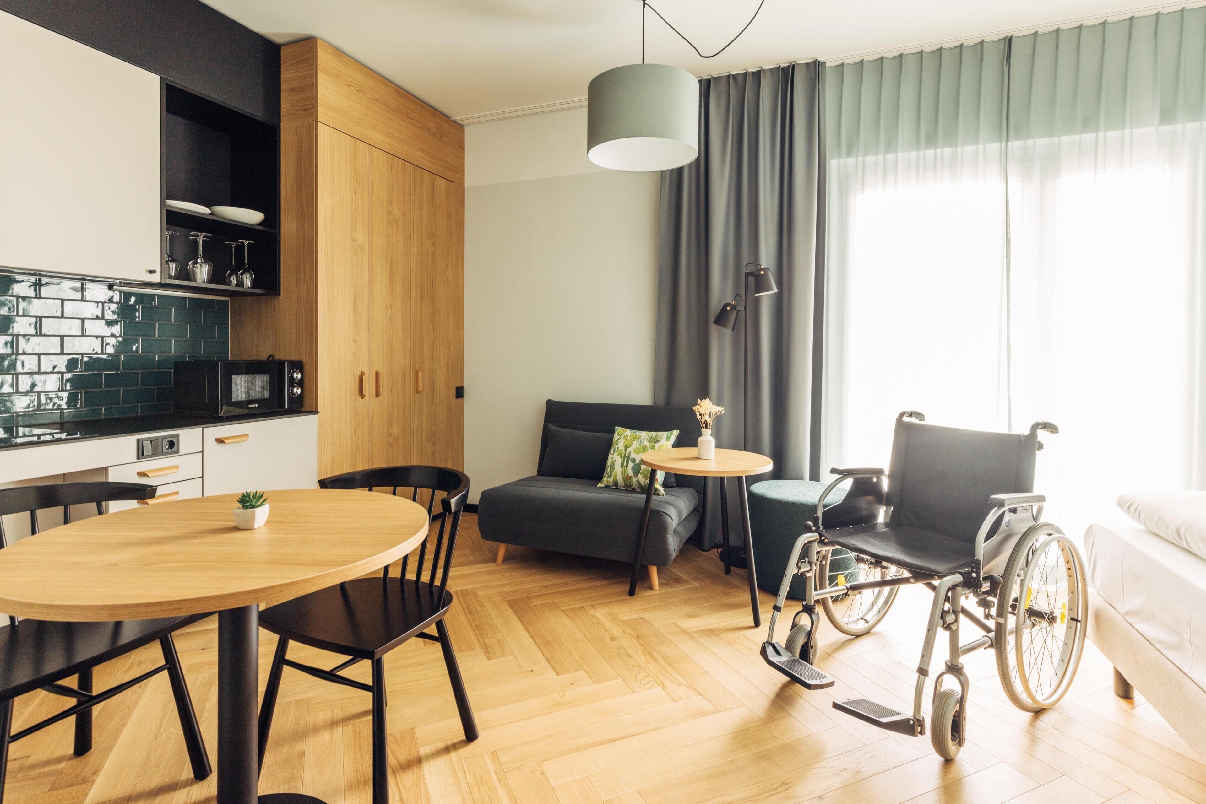 Une cuisine moderne avec un plan de travail noir, des meubles en bois et un coin repas comprenant une table ronde et des chaises.