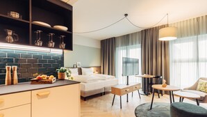 Una habitación de hotel moderna con cama, mesitas de noche, escritorio y zona de comedor.