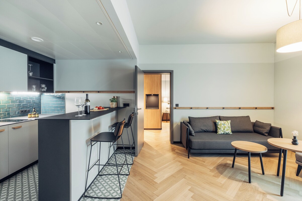 Et moderne køkken med en bar, en siddeplads med sofa og et lille bord, og trægulv.