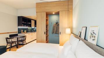 Une chambre d’hôtel moderne équipée d’un lit, d’un bureau et d’une kitchenette.
