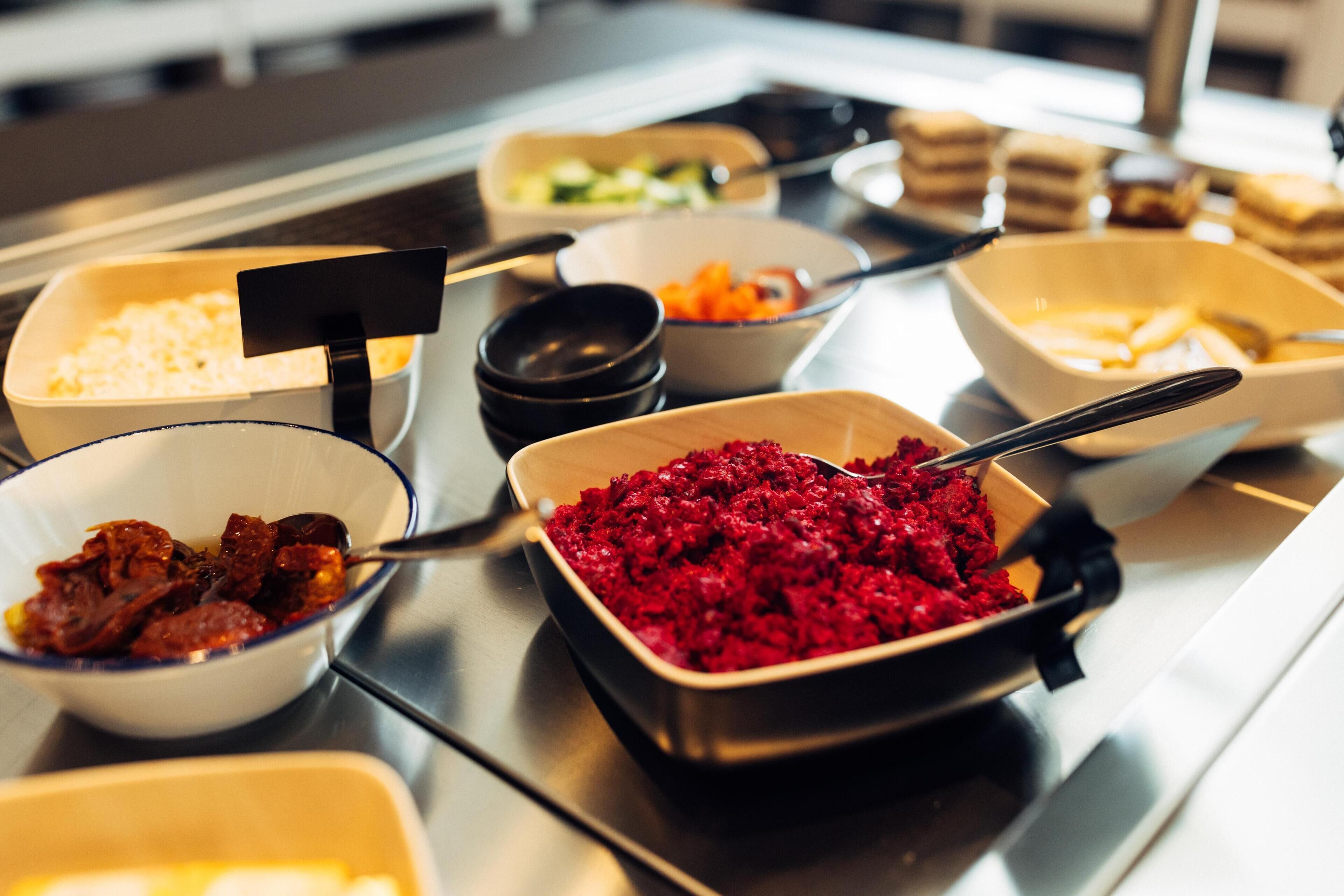 Un bufé con diversos platos, incluyendo un tazón de ensalada de remolacha, un tazón de arroz y un tazón de carne.