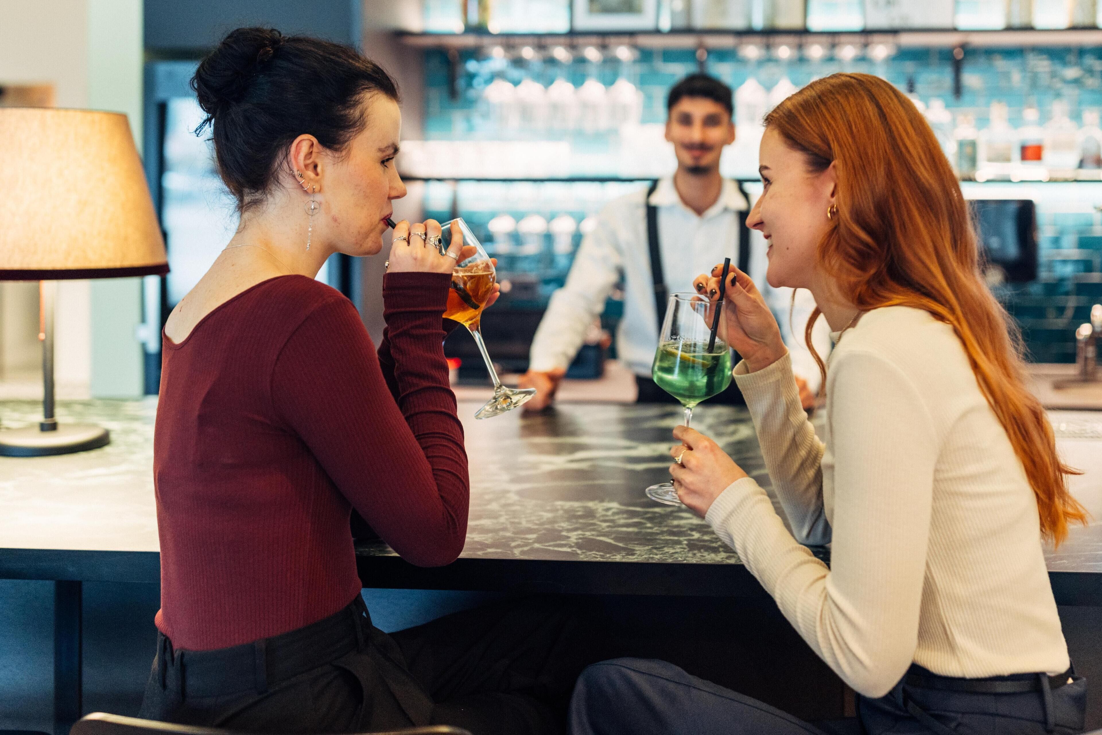 A bar area with a marble countertop and a person holding a glass.